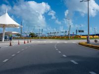 the empty parking lot of the beach side airport in the daytime, with bright clouds overhead