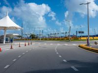 the empty parking lot of the beach side airport in the daytime, with bright clouds overhead