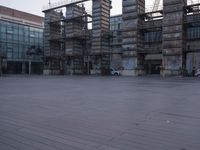 a photo of an empty parking lot with multiple stacks of buildings in the background while there is some smoke coming out from them