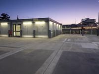 the empty parking lot in front of the building has a flag pole and lights up