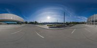 an empty parking lot with a white circular building next to it and the sky behind