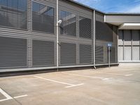 an empty parking lot outside of an industrial warehouse building with metal shutters on the walls