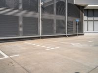 an empty parking lot outside of an industrial warehouse building with metal shutters on the walls