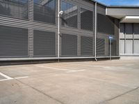 an empty parking lot outside of an industrial warehouse building with metal shutters on the walls