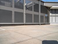 an empty parking lot outside of an industrial warehouse building with metal shutters on the walls