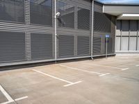 an empty parking lot outside of an industrial warehouse building with metal shutters on the walls