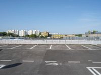 empty parking lot with buildings in the background and white lines painted on asphalt between sides