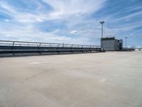 empty parking lot with ramp and railings on sunny day in large industrial area with white sky overhead