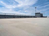 empty parking lot with ramp and railings on sunny day in large industrial area with white sky overhead