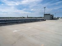 empty parking lot with ramp and railings on sunny day in large industrial area with white sky overhead