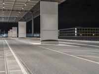 an empty parking lot under a garage at night time with the light on and no traffic