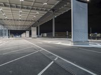 an empty parking lot under a garage at night time with the light on and no traffic