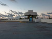 an empty parking lot with a blue door on it's front side against a cloudy sky