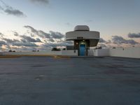 an empty parking lot with a blue door on it's front side against a cloudy sky