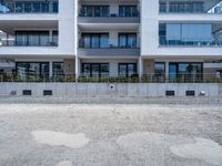 an empty parking lot near a white building in a large block of apartment complex with windows