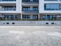 an empty parking lot near a white building in a large block of apartment complex with windows