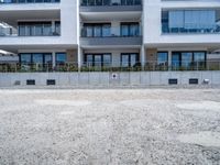 an empty parking lot near a white building in a large block of apartment complex with windows