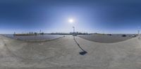 view into an empty parking lot with cars driving by and the sun setting behind it