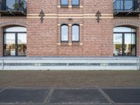 there is an empty parking lot in front of a brick building with many windows on the side