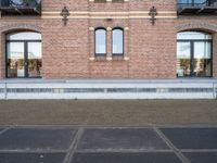 there is an empty parking lot in front of a brick building with many windows on the side