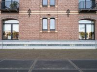 there is an empty parking lot in front of a brick building with many windows on the side