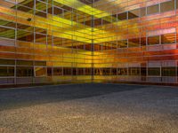 an empty parking lot is illuminated in the sunlight with brightly colored buildings reflected in the windows