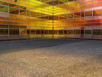 an empty parking lot is illuminated in the sunlight with brightly colored buildings reflected in the windows