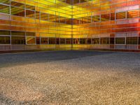 an empty parking lot is illuminated in the sunlight with brightly colored buildings reflected in the windows