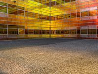 an empty parking lot is illuminated in the sunlight with brightly colored buildings reflected in the windows