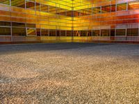 an empty parking lot is illuminated in the sunlight with brightly colored buildings reflected in the windows