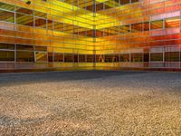 an empty parking lot is illuminated in the sunlight with brightly colored buildings reflected in the windows