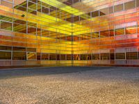 an empty parking lot is illuminated in the sunlight with brightly colored buildings reflected in the windows