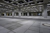 empty concrete parking lot with columns and suspended lights in the center of the building at night