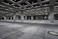 empty concrete parking lot with columns and suspended lights in the center of the building at night