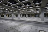 empty concrete parking lot with columns and suspended lights in the center of the building at night