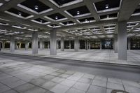 empty concrete parking lot with columns and suspended lights in the center of the building at night