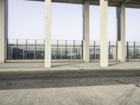 an empty parking lot and building with multiple pillars on either side of it, which are empty