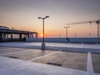 a parking lot with lots of empty parking lot space at sunset time with a building in the background