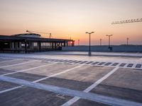 a parking lot with lots of empty parking lot space at sunset time with a building in the background