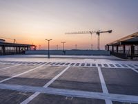 a parking lot with lots of empty parking lot space at sunset time with a building in the background