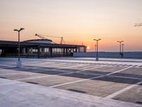 a parking lot with lots of empty parking lot space at sunset time with a building in the background