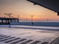 a parking lot with lots of empty parking lot space at sunset time with a building in the background