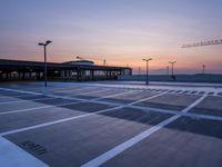 a parking lot with lots of empty parking lot space at sunset time with a building in the background