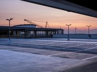 a parking lot with lots of empty parking lot space at sunset time with a building in the background