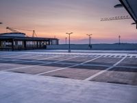 a parking lot with lots of empty parking lot space at sunset time with a building in the background