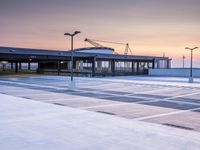 a parking lot with lots of empty parking lot space at sunset time with a building in the background