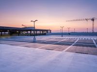 a parking lot with lots of empty parking lot space at sunset time with a building in the background