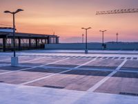 a parking lot with lots of empty parking lot space at sunset time with a building in the background