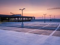 a parking lot with lots of empty parking lot space at sunset time with a building in the background