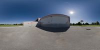 a fisheye lens photo of an empty parking lot with a building behind it and a sign for a stop sign next to the entrance